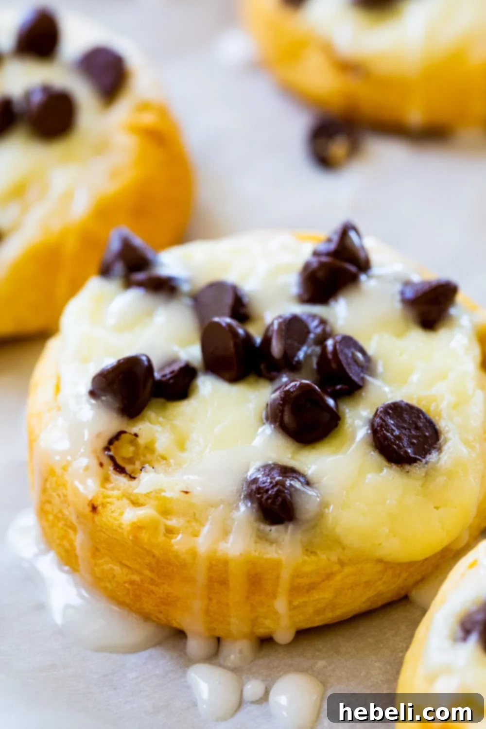A close-up shot of a single Chocolate Chip Cream Cheese Danish, showing the flaky crust, melted chocolate, and creamy filling, with a light glaze.