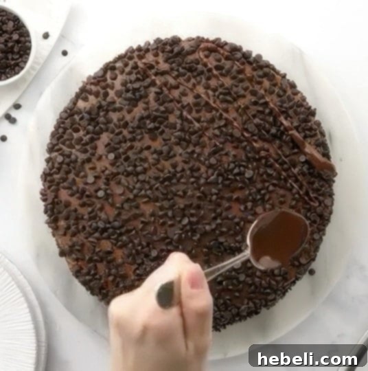 Rich, melted chocolate ganache being skillfully drizzled over the frosted Death By Chocolate Cake, creating an irresistible and artistic finish.