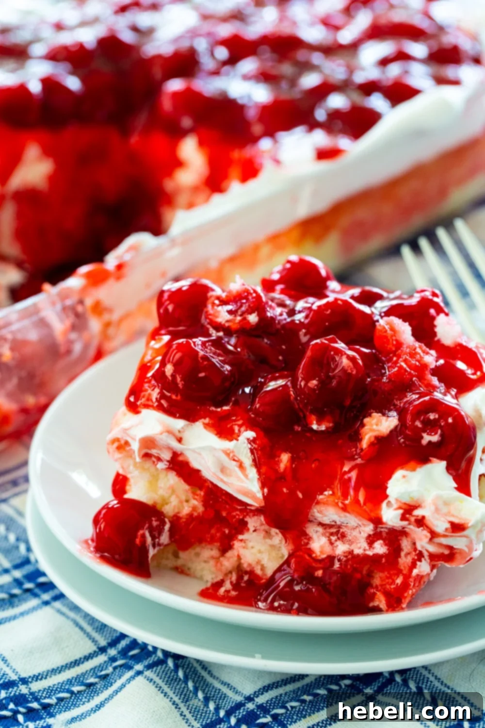 A beautifully plated slice of Cherry Poke Cake, adorned with cherries, ready to be enjoyed as a refreshing dessert.