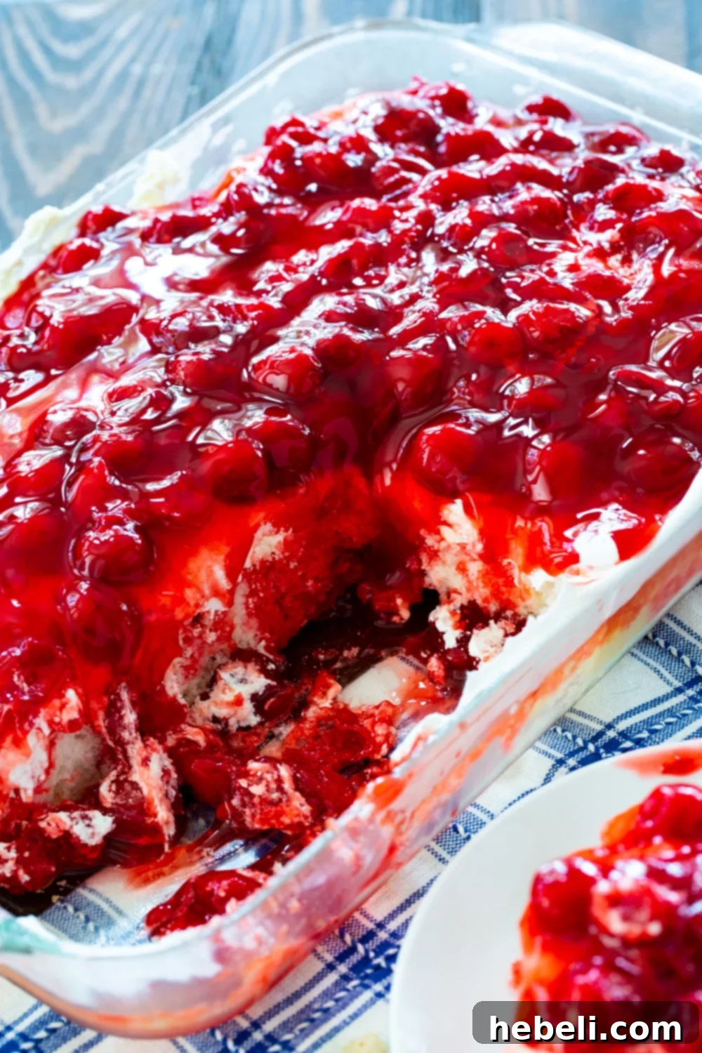 A gorgeous Cherry Poke Cake, complete with cherry topping, sitting in a 9x13-inch baking pan, ready to be served.