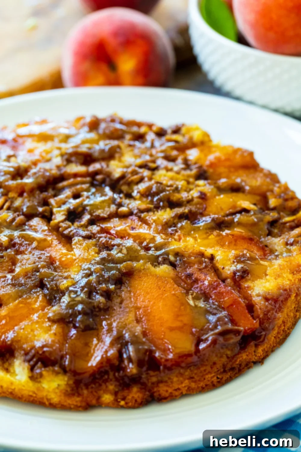 A whole, beautifully baked Peach Praline Upside Down Cake, showcased on a pristine white plate, promising a delightful dessert experience.