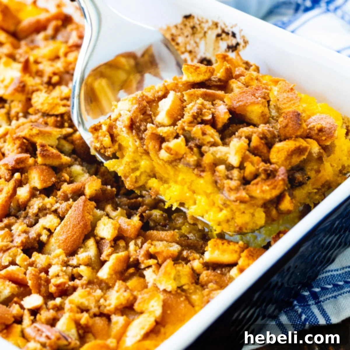 A serving of creamy Butternut Squash Casserole with a spatula, showcasing the crumb topping.