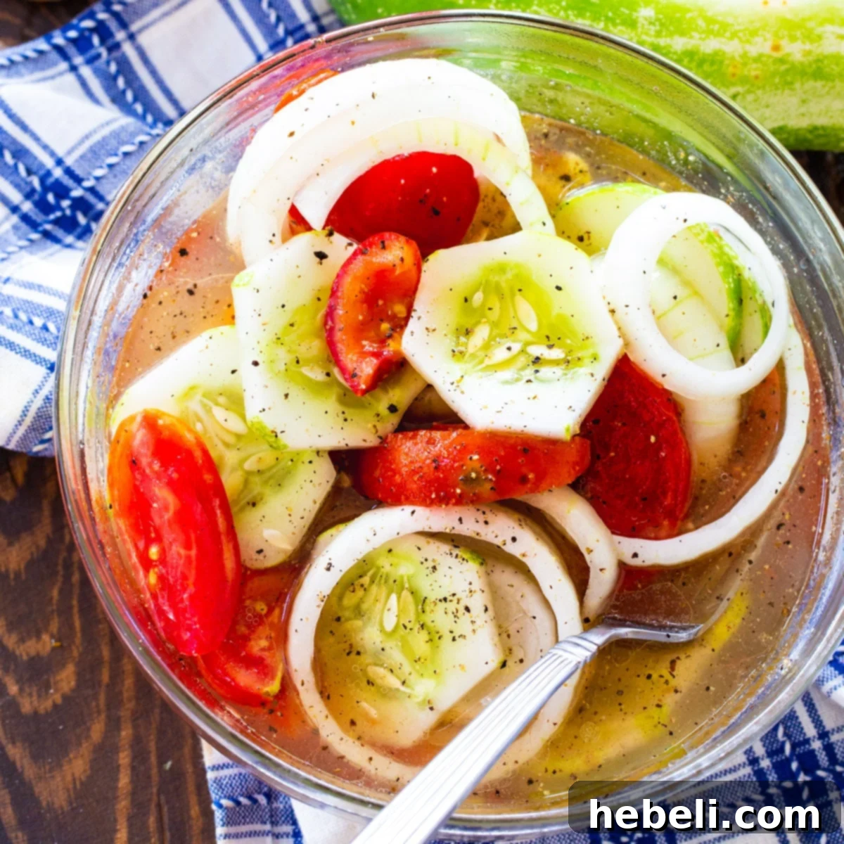 Vibrant Marinated Cucumber, Tomato, and Onion Salad in a clear glass serving bowl, showcasing its fresh ingredients.