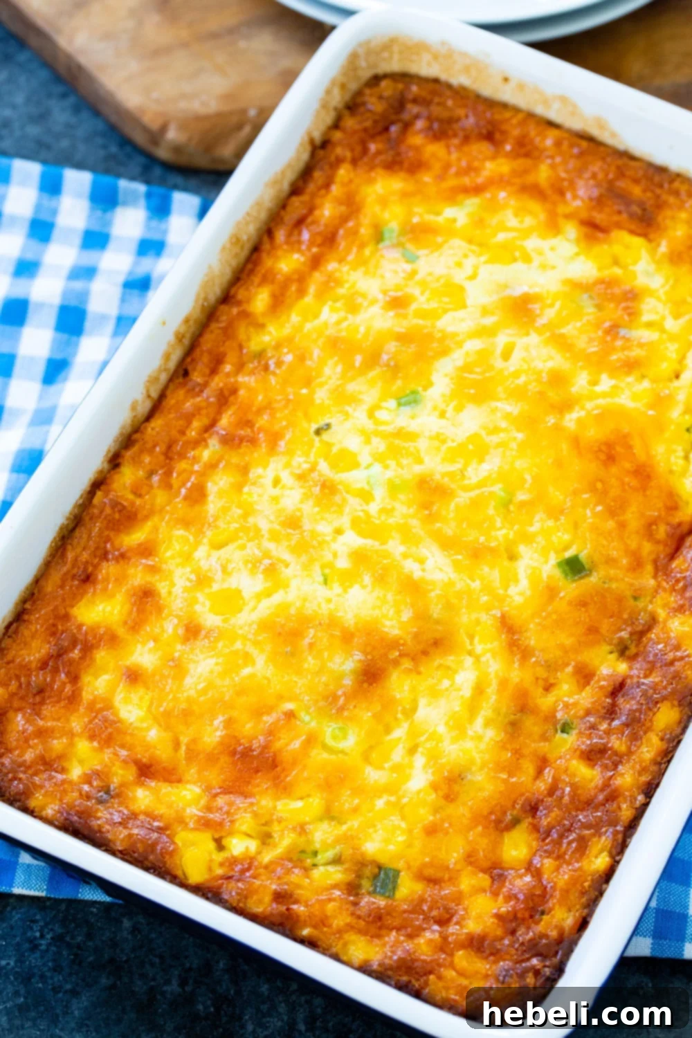 A golden-brown corn casserole baking in a ceramic dish, ready to be served.