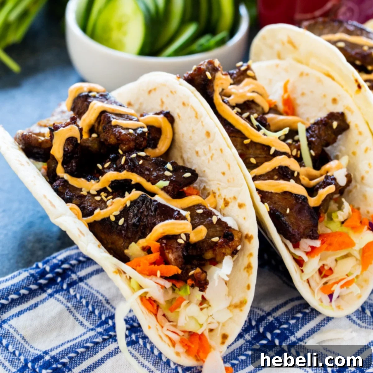 Korean BBQ Tacos 2 Two vibrant Korean Bulgogi Tacos, showcasing sweet and spicy beef, crisp slaw, and a creamy Gochujang drizzle.