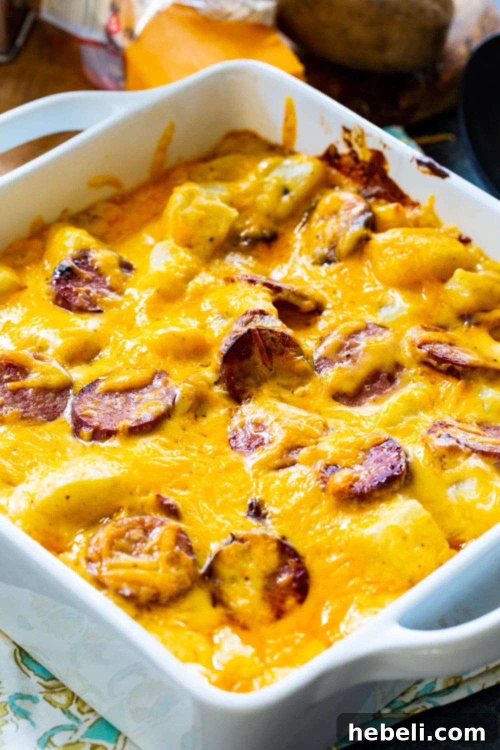 Close-up of Cheesy Potatoes with Smoked Sausage in a white baking dish, showing rich cheese sauce and sausage slices.