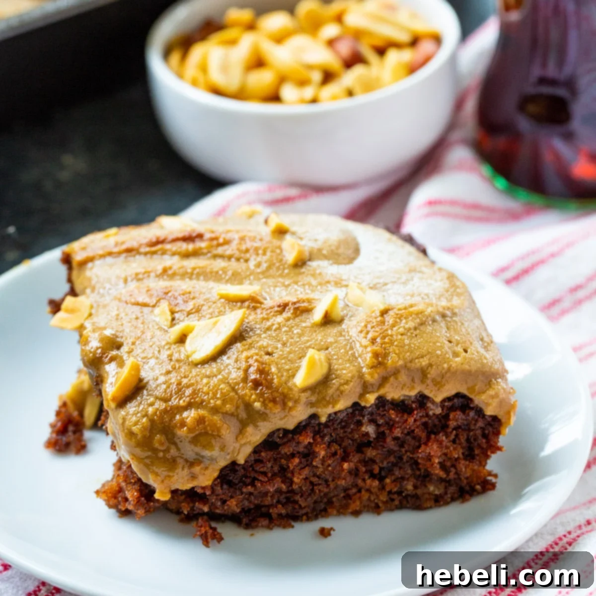 A delectable slice of Coca-Cola Cake with Broiled Peanut Frosting served on a plate, showcasing its rich, moist chocolate base and golden-brown, toasted peanut butter topping.