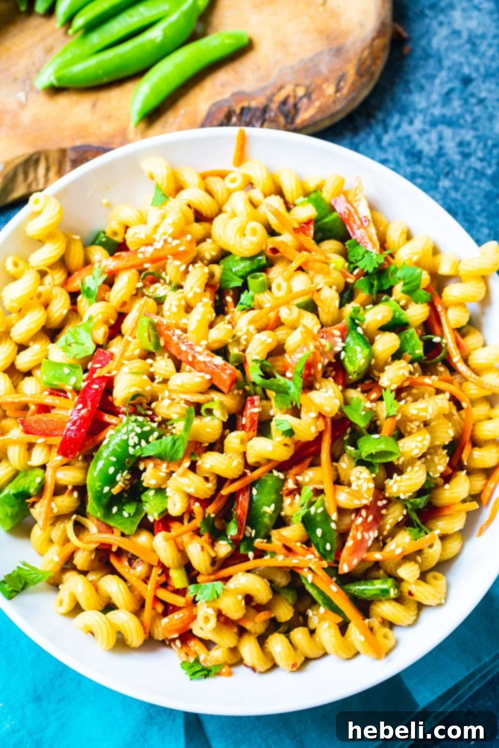 Asian Fusion Pasta Salad 3 An overhead shot of Asian Pasta Salad in a clean white bowl, highlighting the intricate mix of ingredients and the appealing sheen of the sesame/soy dressing.