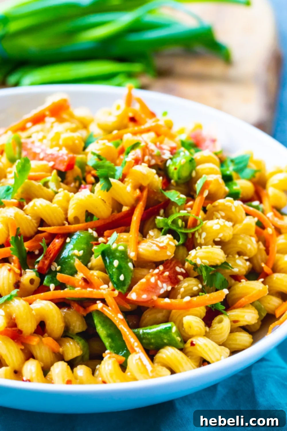 Asian Fusion Pasta Salad 4 A close-up of Asian Pasta Salad in a white bowl, showing the texture of the pasta and the variety of ingredients like snap peas, carrots, and the glossy soy dressing.