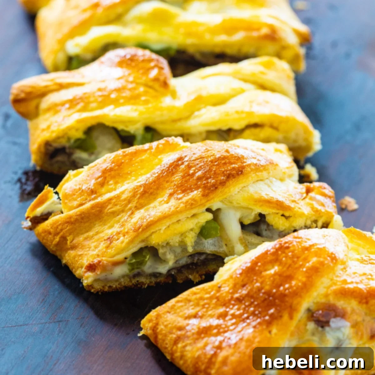 A perfectly baked Cheesesteak Crescent Braid, sliced to reveal the delicious beef, onion, pepper, and melted cheese filling.