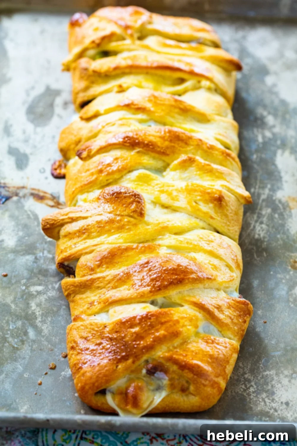 Baked Cheesesteak Crescent Braid cooling on a baking sheet, showcasing its golden crust and delicious aroma.