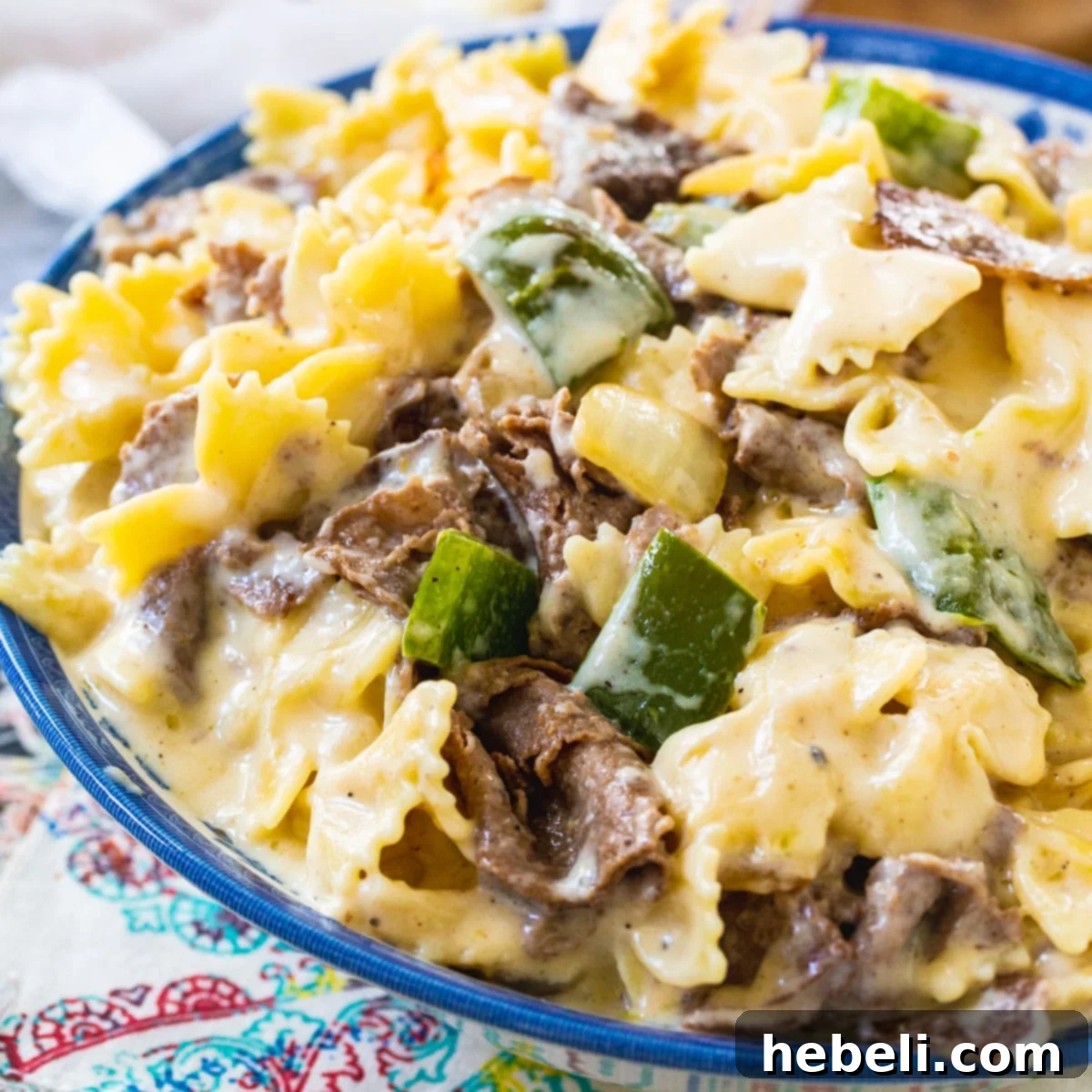 Ultimate Philly Cheesesteak Mac 2 Rich and creamy Philly Cheesesteak Mac and Cheese in a rustic blue and white bowl, garnished with fresh parsley.