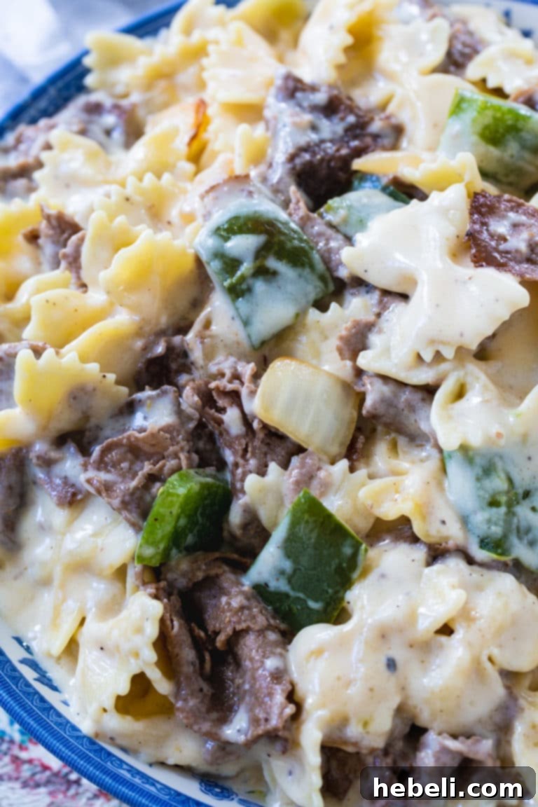 Ultimate Philly Cheesesteak Mac 4 Appetizing Philly Cheesesteak Mac and Cheese served in a ceramic bowl, highlighting the generous portions of steak, peppers, and onions within the creamy pasta.