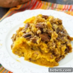 Serving of Crock Pot Sweet Potato Casserole on a plate, garnished with more pecans.