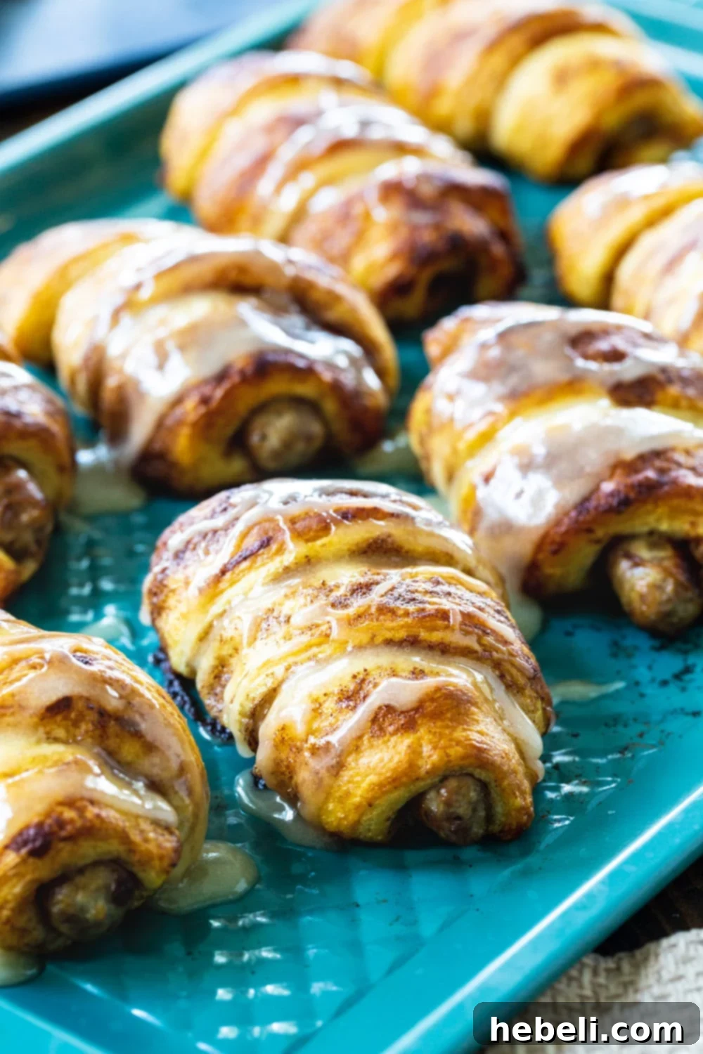 Ingredients for Cinnamon Roll Pigs in a Blanket: a can of cinnamon rolls, sausage links, and maple syrup.