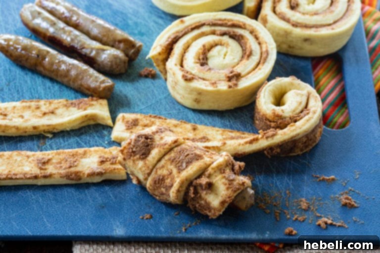 Freshly baked Cinnamon Roll Pigs in a Blanket on a parchment-lined baking sheet, glistening with glaze.