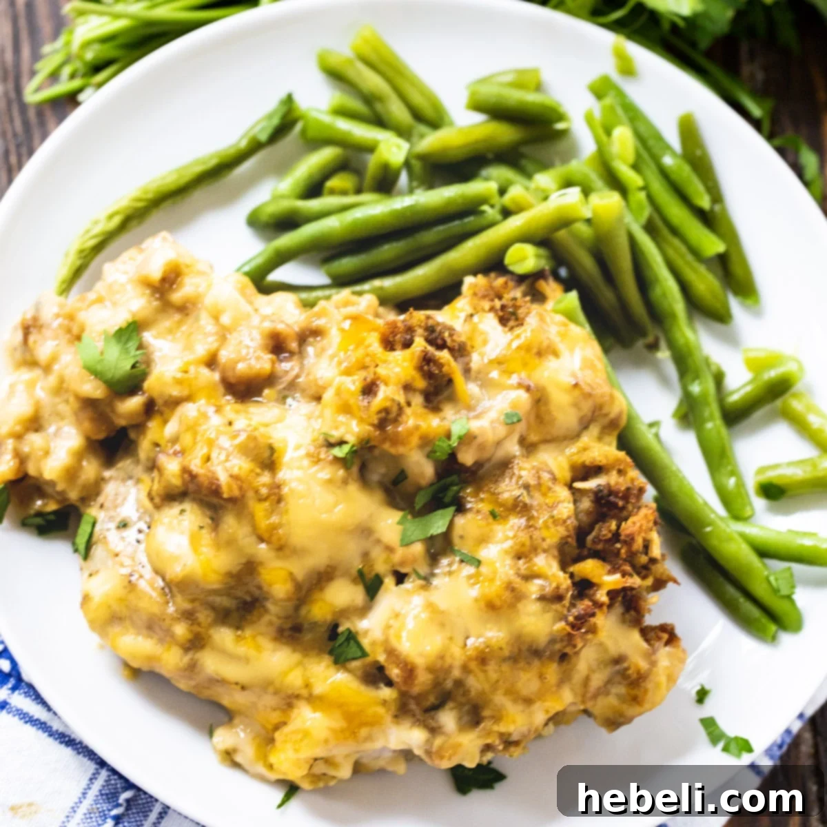 Savory Stuffing-Crusted Pork Chops 2 Stuffing Topped Pork Chop on a plate with fresh steamed green beans, ready to be enjoyed.