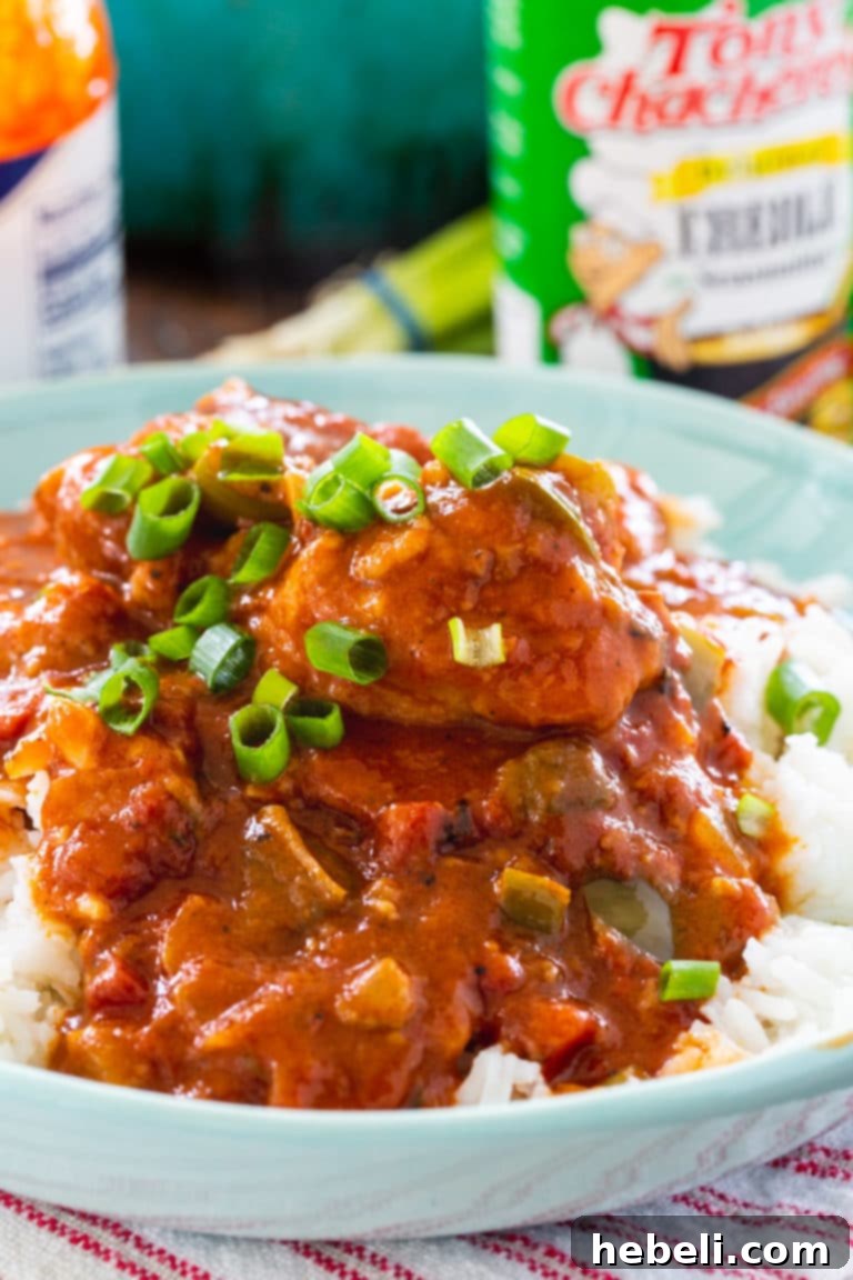 A close-up shot of Chicken Sauce Piquant generously served in a bowl with white rice, garnished with green onions.