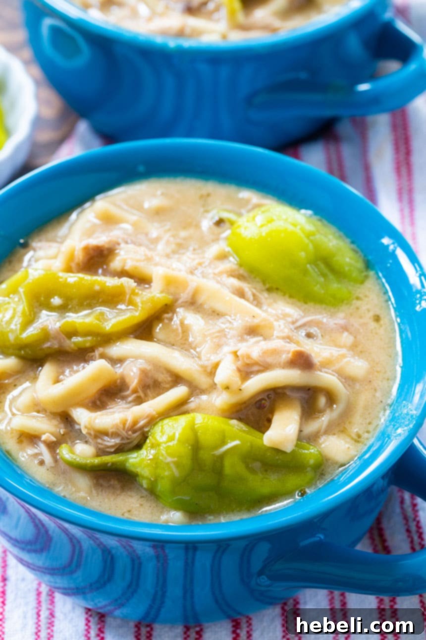 A generous serving of Slow Cooker Mississippi Chicken and Noodles with visible pepperoncini peppers.