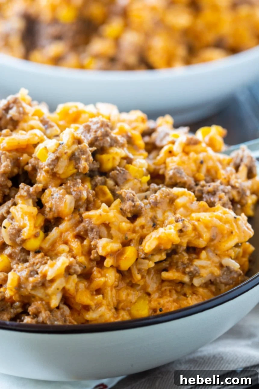 Bowl of Instant Pot Cheesy Ground Beef and Rice with a spoon.