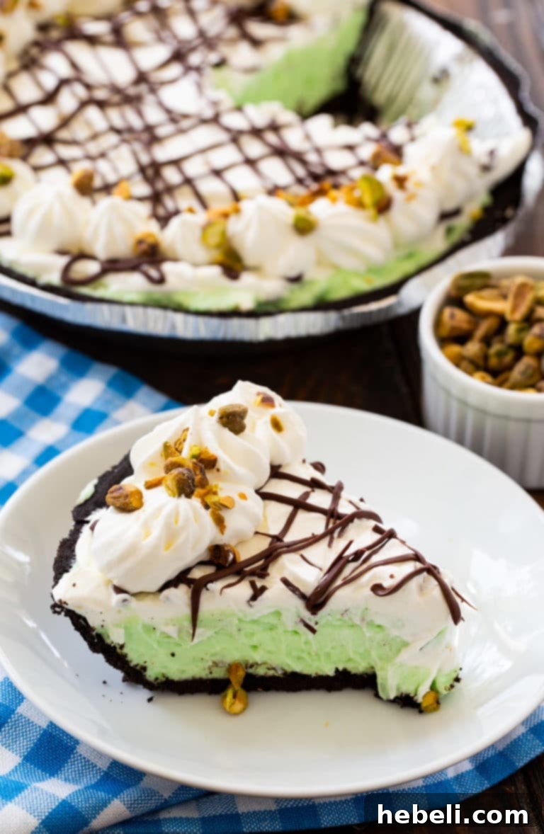 Velvety No-Bake Pistachio Pie 3 Full No-Bake Pistachio Pudding Pie, beautifully plated and ready to serve, showcasing its vibrant green filling and creamy topping.