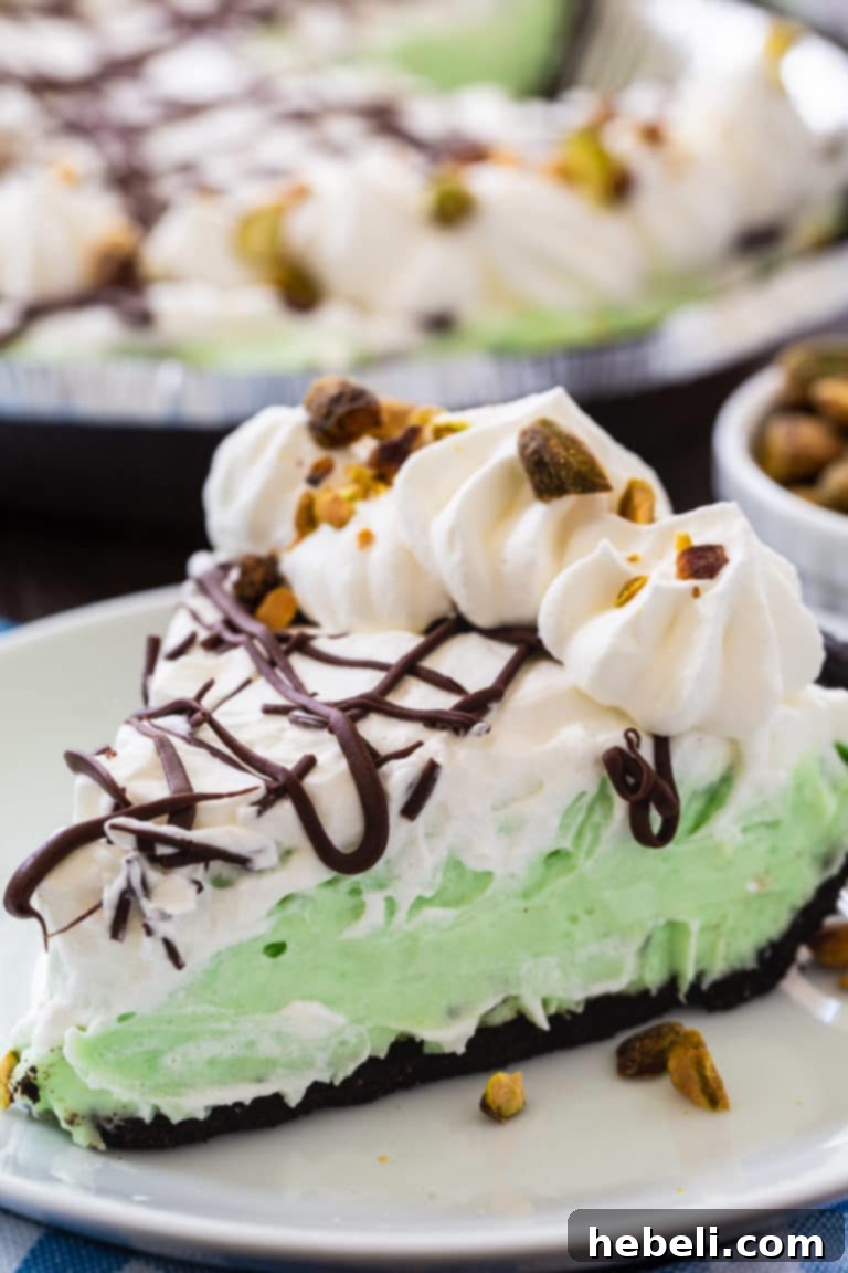 Velvety No-Bake Pistachio Pie 4 Close-up of No-Bake Pistachio Pudding Pie in an Oreo crust, showing the delicate chocolate drizzle and finely chopped pistachios on top of the whipped cream.