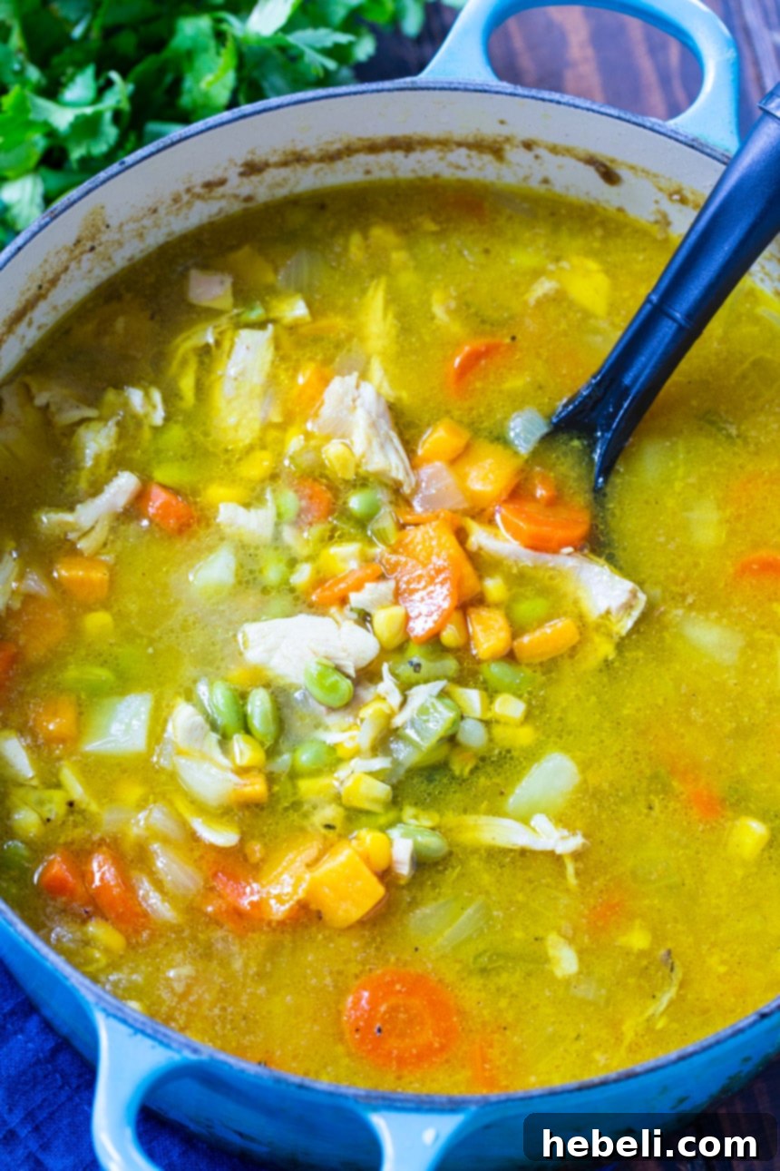 A Dutch oven filled with a rich, yellow curried chicken chowder, ready to be served.