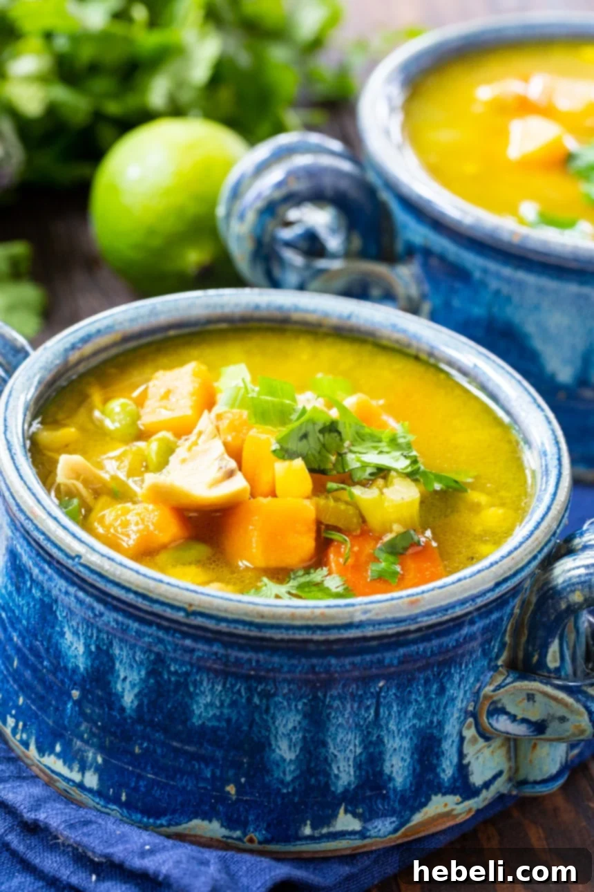 A close-up shot of Curried Chicken Chowder in a bowl, garnished with fresh herbs and a lime wedge