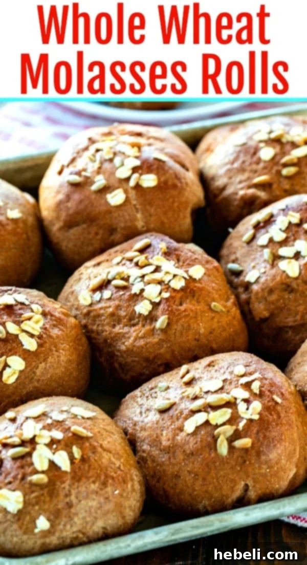 Stacked Whole Wheat Molasses Rolls on a wooden board, garnished with fresh herbs.