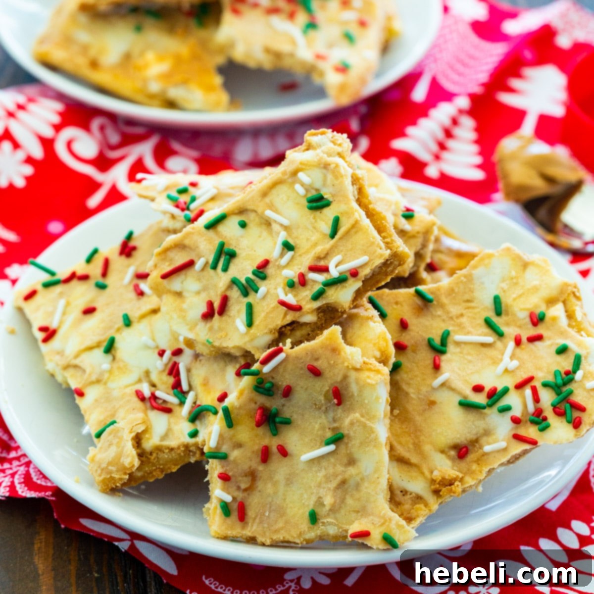 Decadent White Chocolate Peanut Butter Christmas Crack 2 Delicious pieces of White Chocolate and Peanut Butter Christmas Crack piled high on a festive plate, ready to be enjoyed or shared.