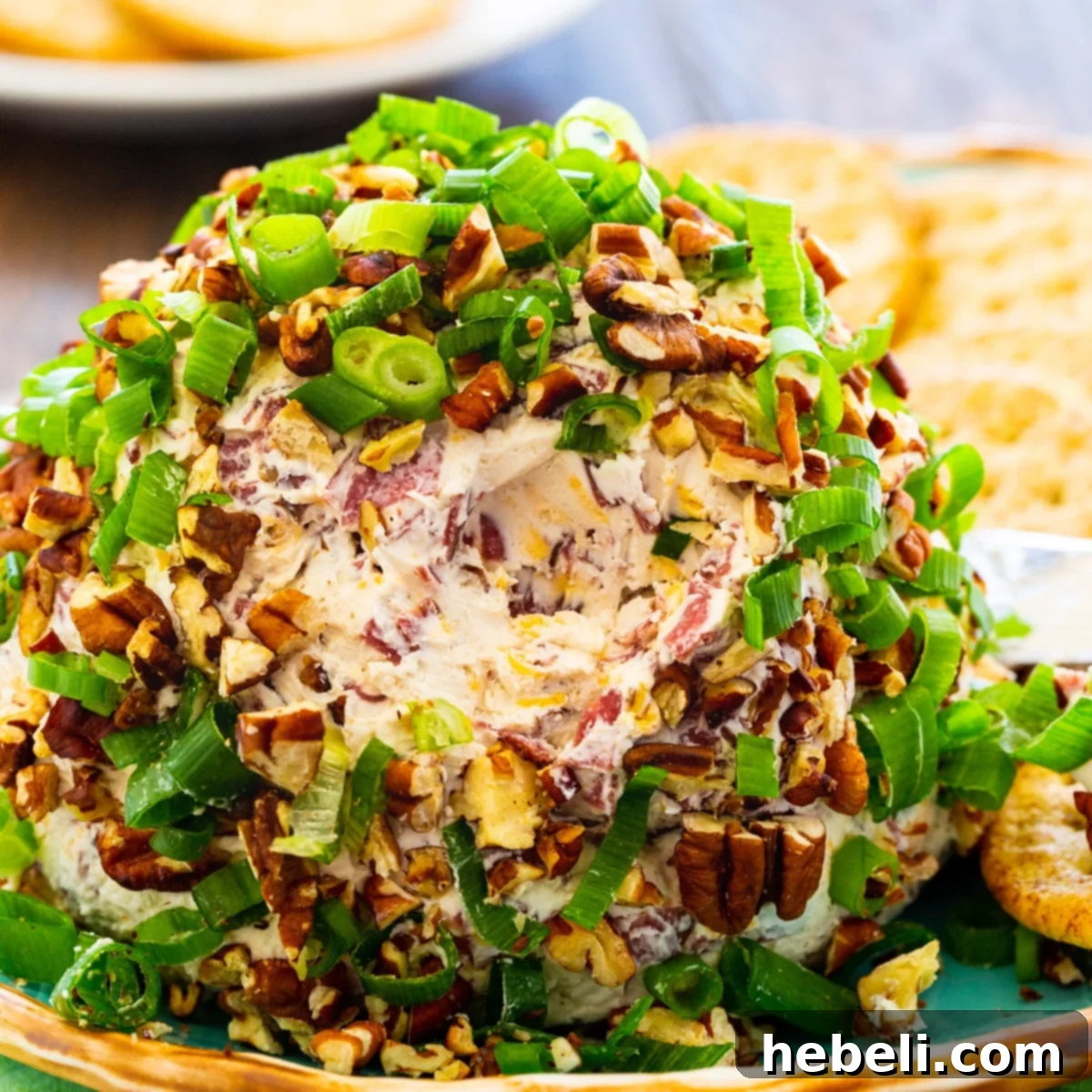 A festive Chipped Beef Cheese Ball, generously covered with green onions and chopped toasted pecans, served on a platter with crackers.