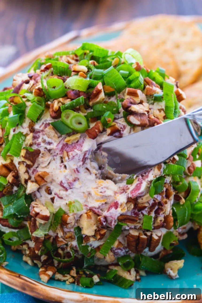 A beautifully presented Chipped Beef Cheese Ball on a wooden serving board, surrounded by an assortment of crackers and ready for a party.