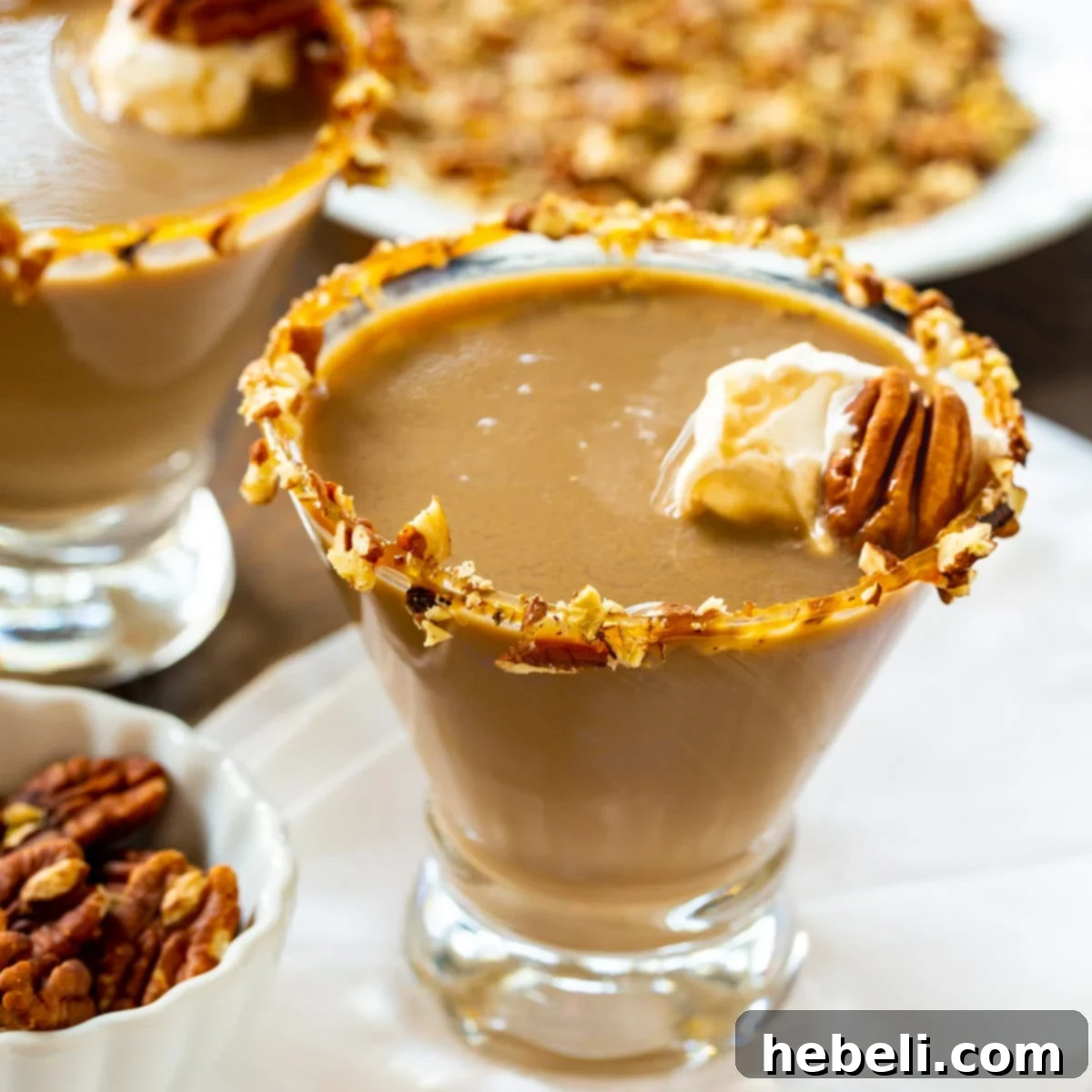 A beautifully garnished Pecan Pie Martini with a caramel and chopped pecan rim, ready to be enjoyed.