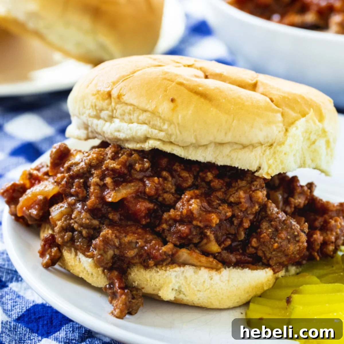 Sloppy Joe on a bun with pickle slices, ready to be enjoyed.