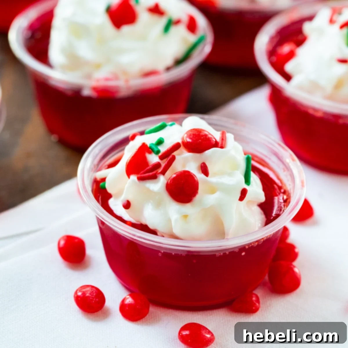 Fireball Jell-O Shots 2 Vibrant Fireball Jello Shots topped with fluffy whipped cream and colorful sprinkles, ready for a festive celebration.