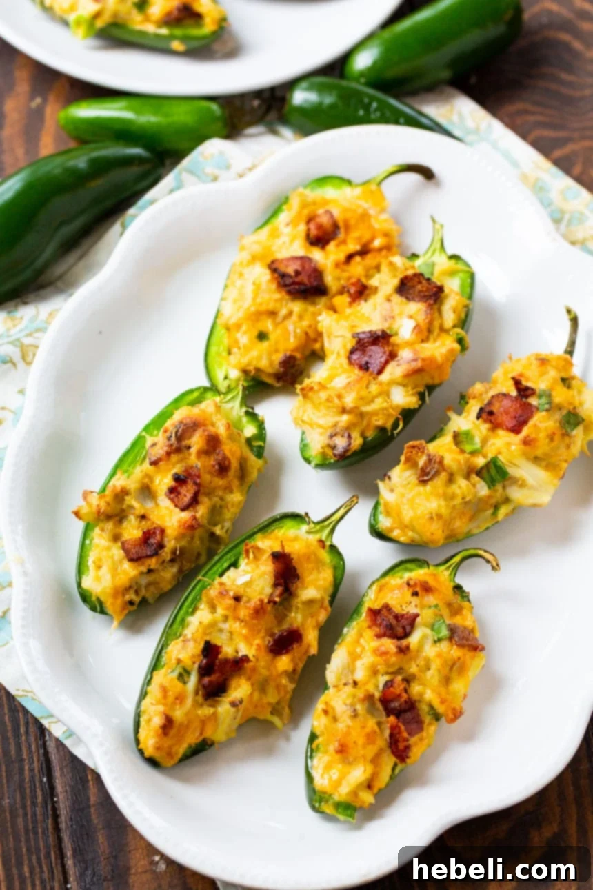 Close-up view of baked Cajun Crab Stuffed Jalapenos, highlighting the crispy bacon and melted cheddar cheese topping.