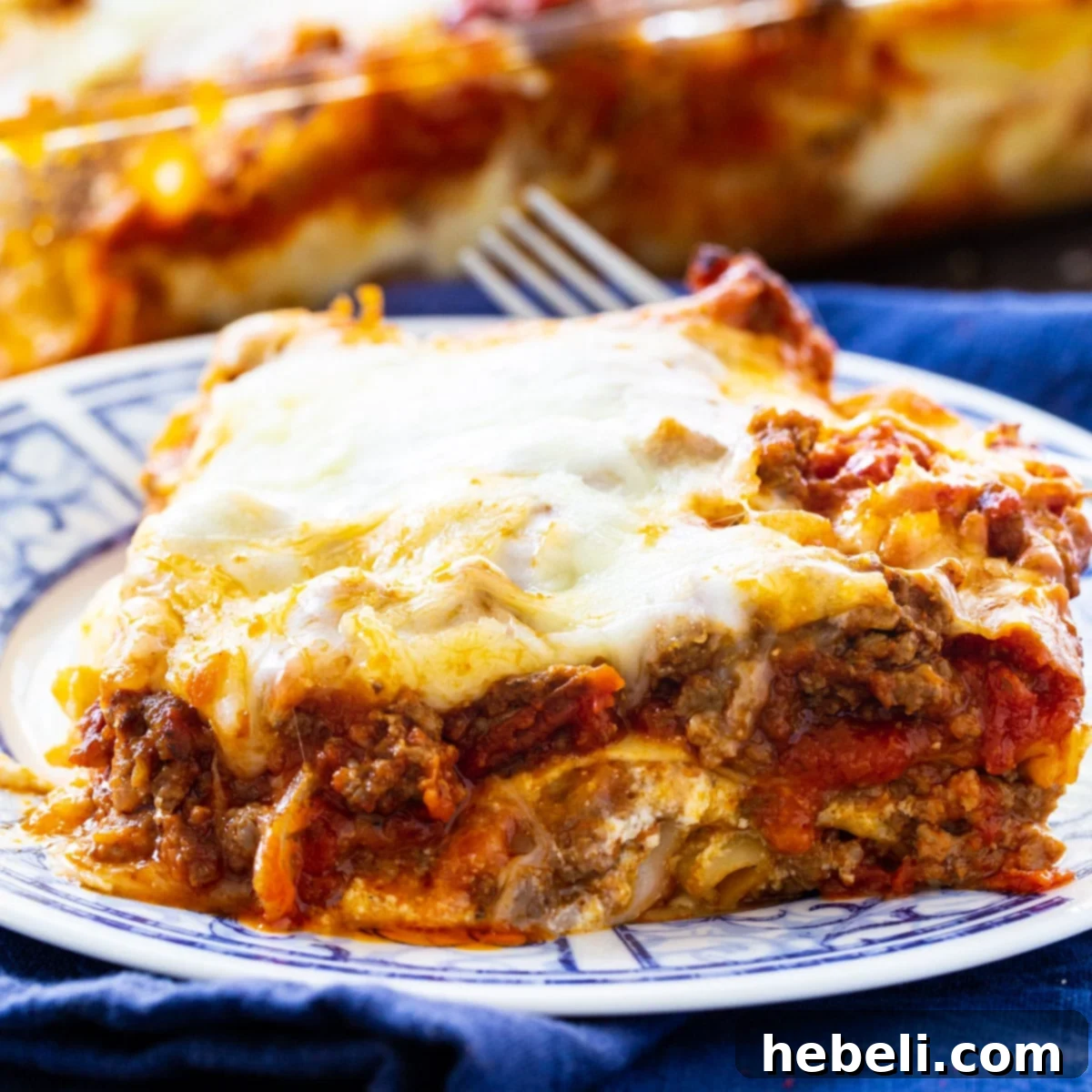 A generous slice of Make-Ahead Lasagna on a white plate, showcasing its layers of pasta, rich meat sauce, and melted cheese.