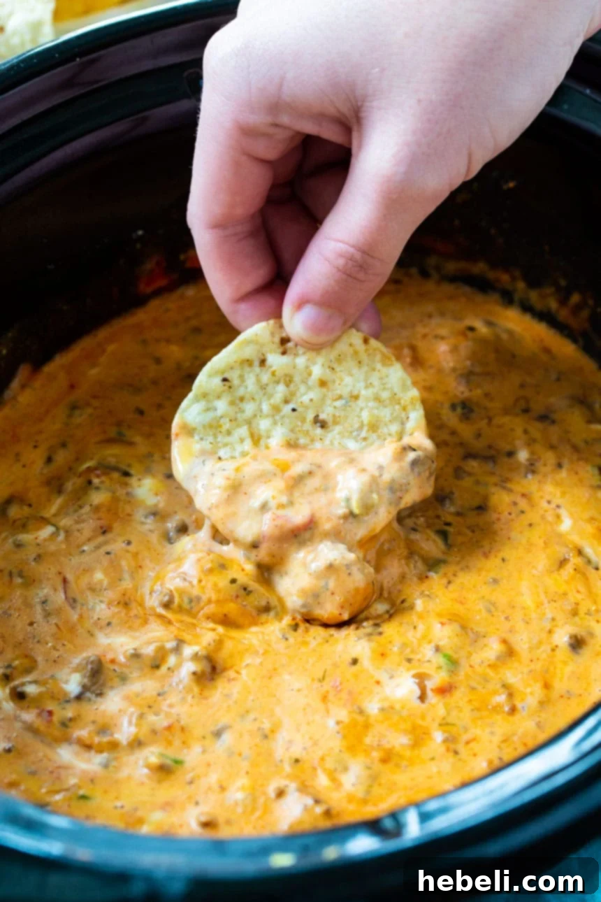 Creamy Slow Cooker Taco Dip 3 A tortilla chip generously scooping up creamy, cheesy Slow Cooker Cream Cheese Taco Dip.