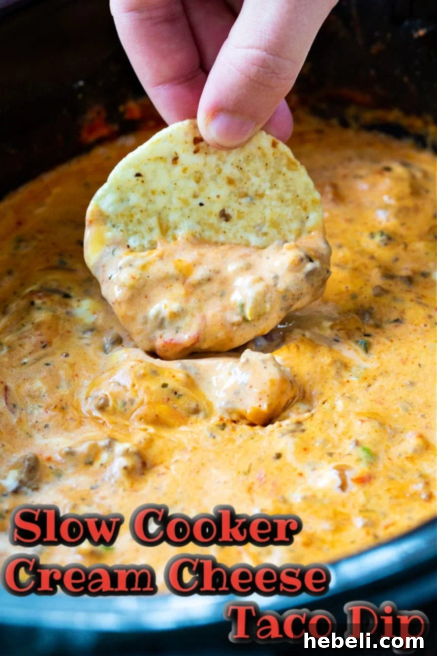Creamy Slow Cooker Taco Dip 4 Close-up of a chip scooping a generous amount of Slow Cooker Cream Cheese Taco Dip, highlighting its rich texture.