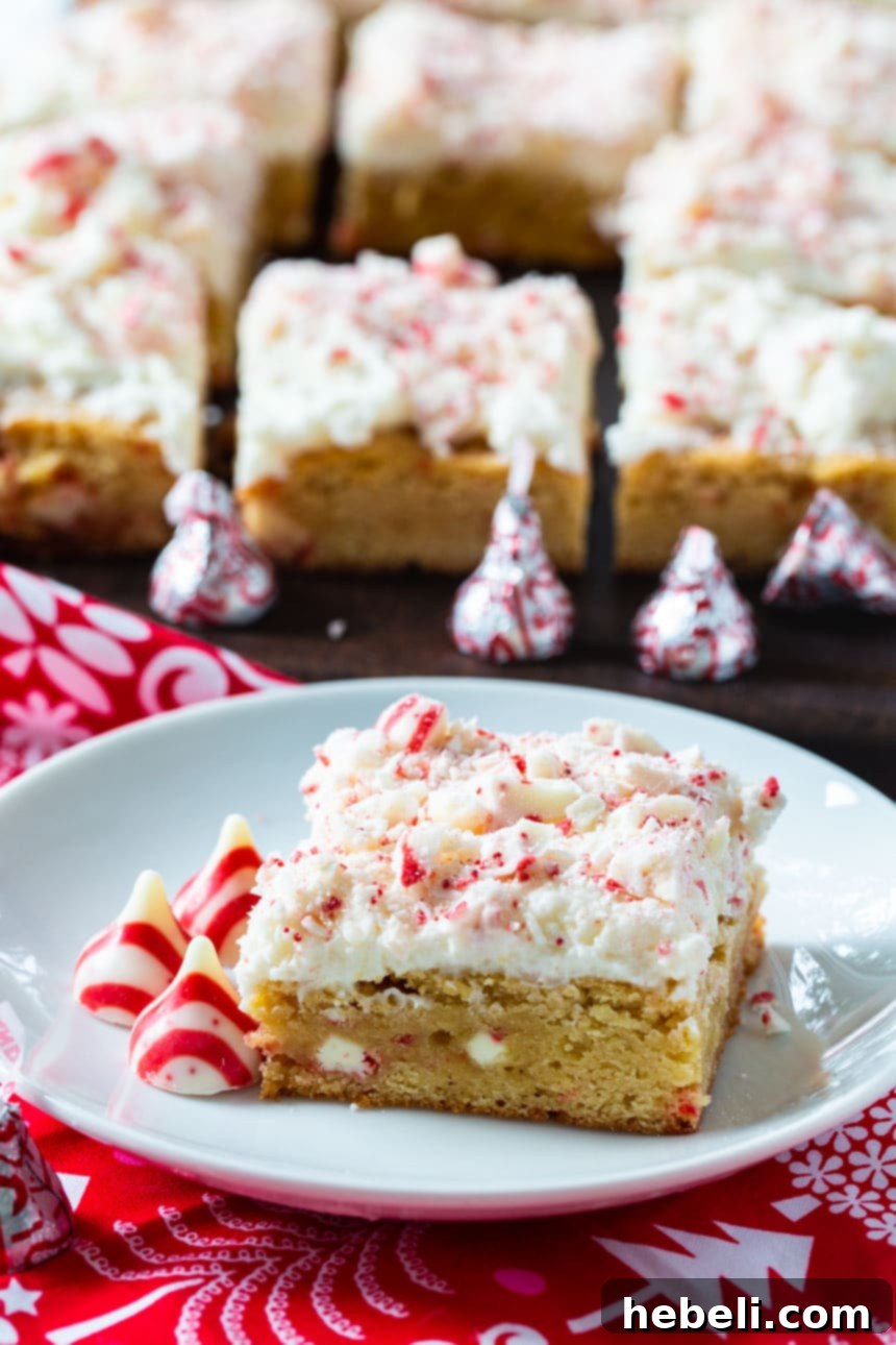 A single Peppermint Blondie with buttercream on a small white plate, with more blondies blurred in the background.