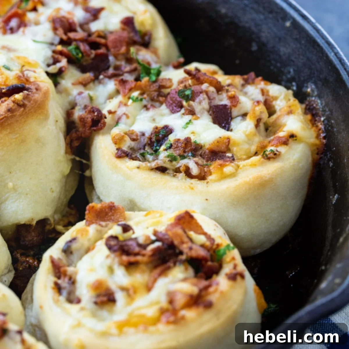 Golden brown Bacon Stuffed Cheesy Garlic Rolls, fresh out of the oven in a cast iron pan, showcasing melted cheese and visible bacon bits.