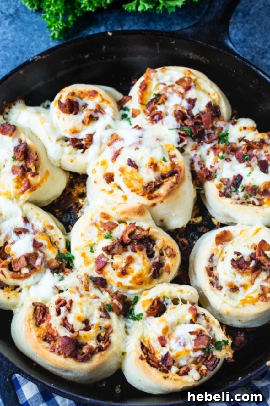 Bacon and cheese filled pizza dough, rolled and ready for slicing, resembling a savory pinwheel log.