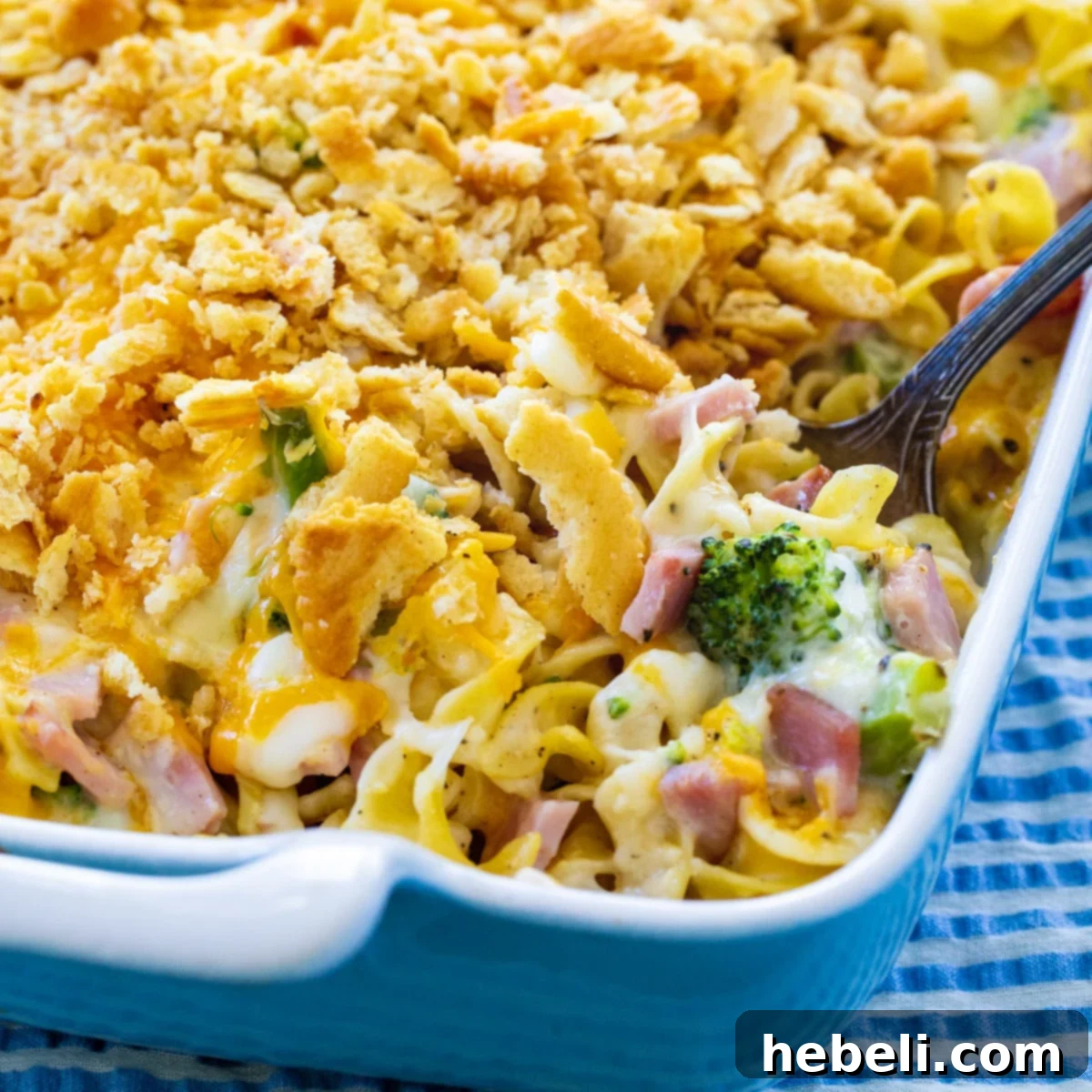 Hearty Ham and Broccoli Noodle Bake 2 Spoon scooping up a portion of creamy Ham and Noodle Casserole with Broccoli, showcasing its rich texture and cheesy goodness.