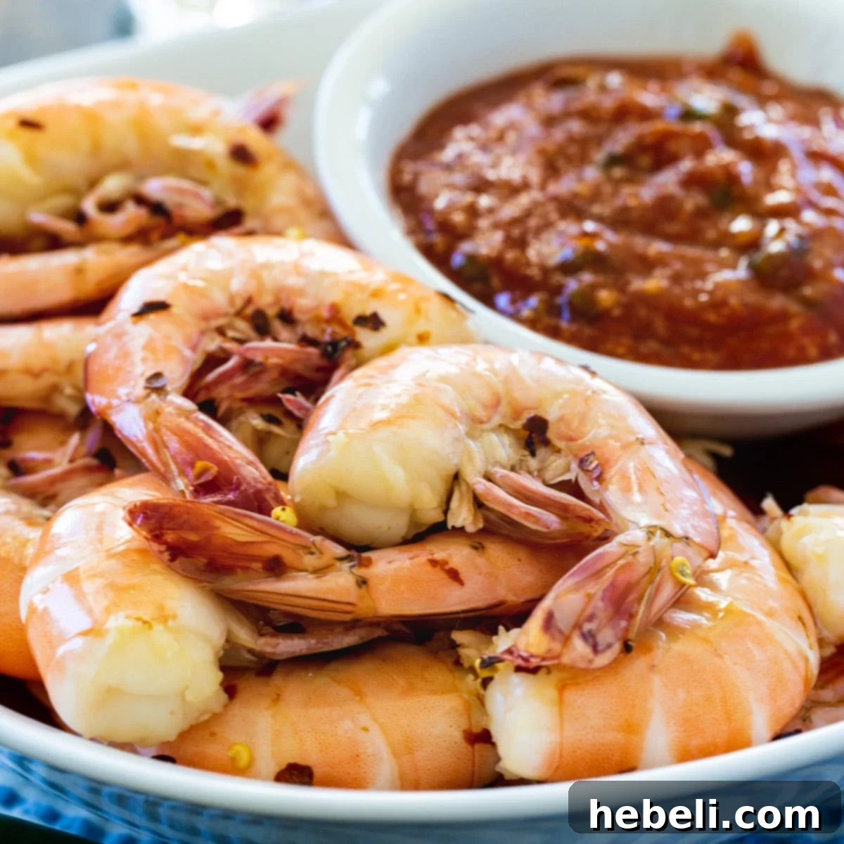 Drunken Shrimp with Fire Roasted Jalapeno Kick 2 Perfectly cooked Drunken Shrimp served on a rustic plate, with a small bowl of fiery Roasted Jalapeno Cocktail Sauce on the side, ready for peeling and eating.