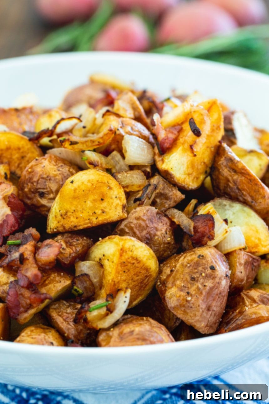 Close-up view of golden and crispy Italian Roasted Potatoes with flecks of green rosemary and red pancetta.