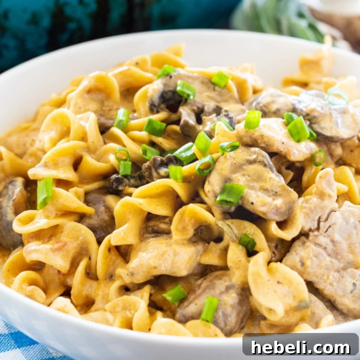 A bowl of creamy Pork Stroganoff garnished with fresh herbs, ready to be served.