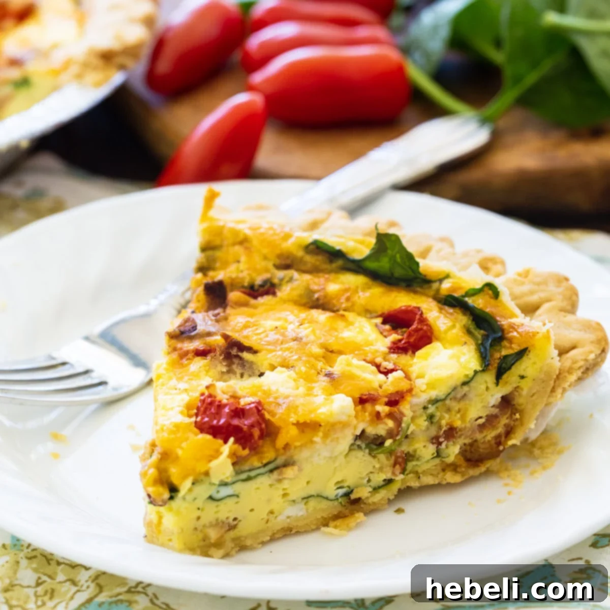 A delectable slice of BLT Quiche showcasing layers of bacon, spinach, and tomatoes on a white plate, ready to be enjoyed.
