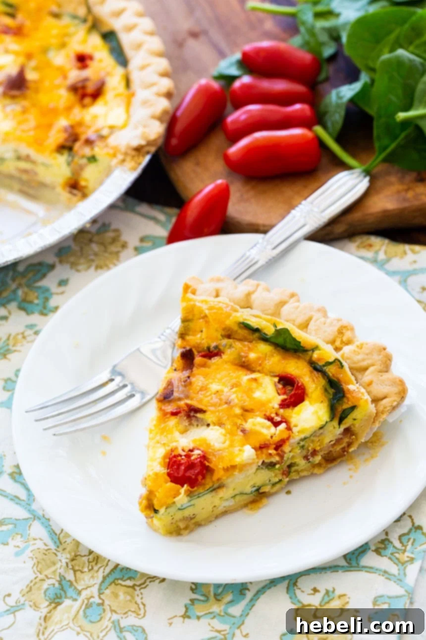 Close-up of BLT Quiche showcasing the browned bacon, bright red cherry tomatoes, and green spinach baked into the egg custard.
