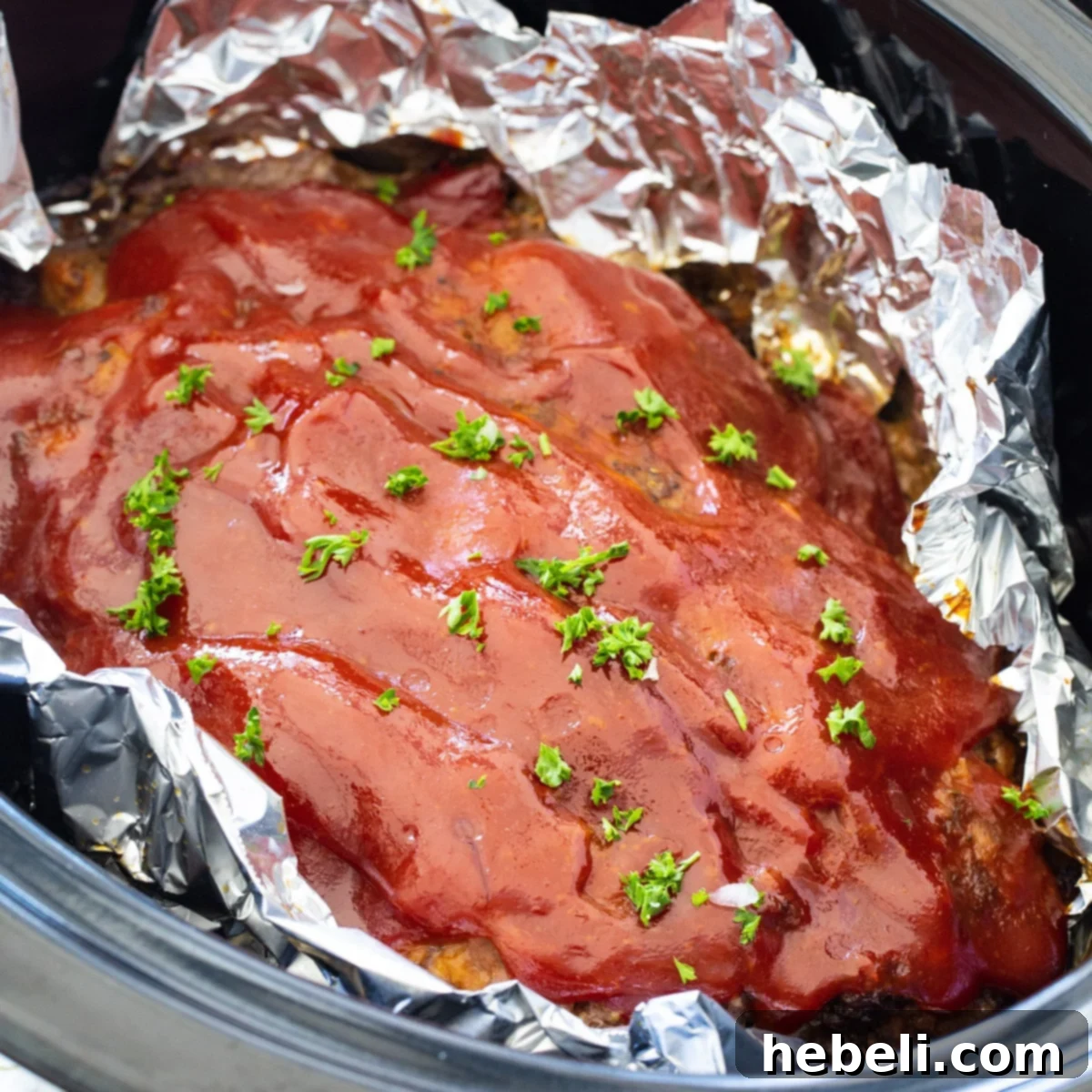 Crockpot Meatloaf lined with aluminum foil in slow cooker.