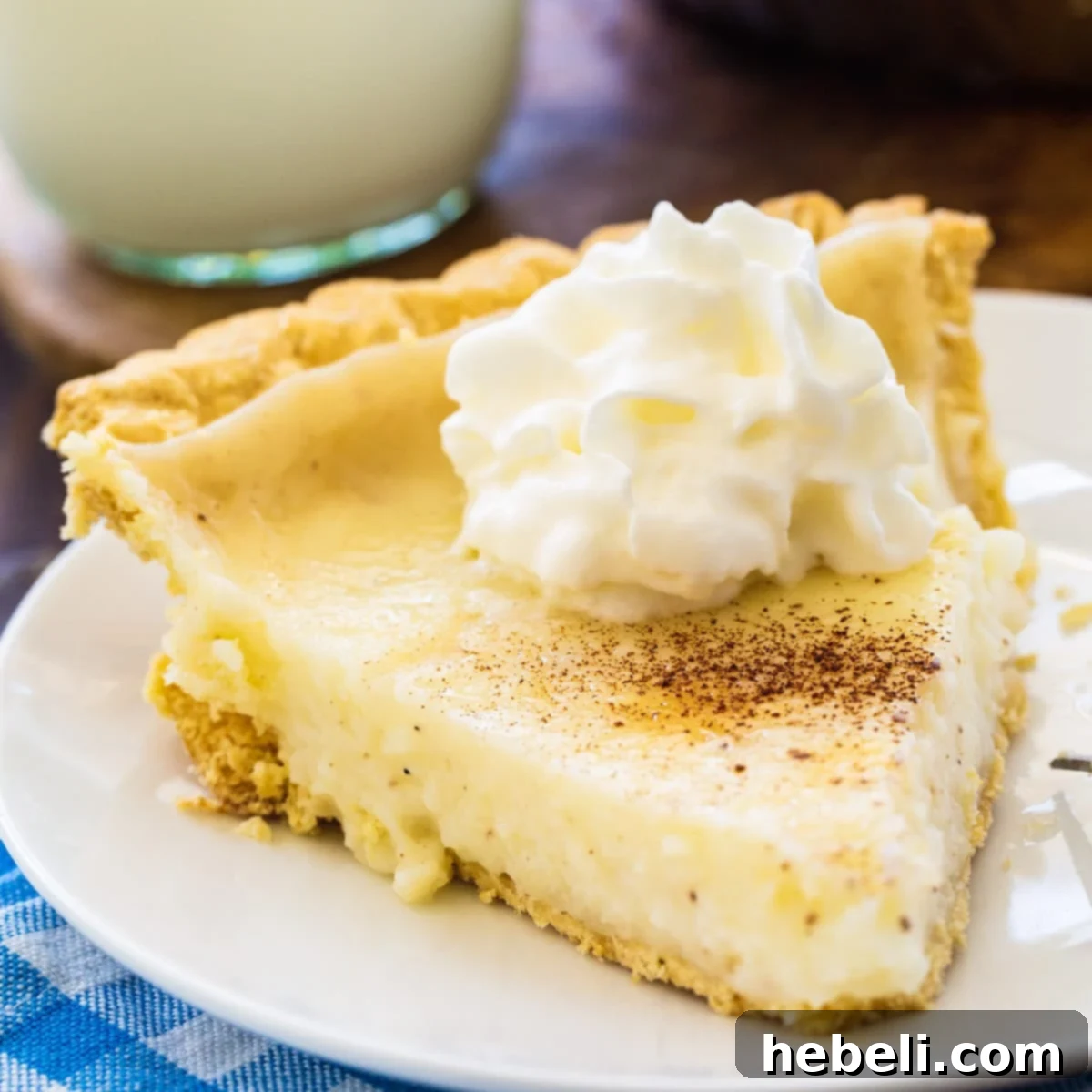 A perfectly sliced Sugar Cream Pie topped with a generous swirl of whipped cream, ready to be enjoyed.